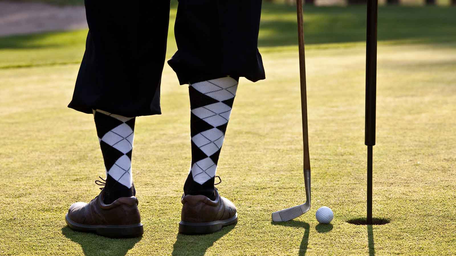 Man standing by the pin on a putting green.