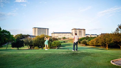 Woman teeing off on the golf course.