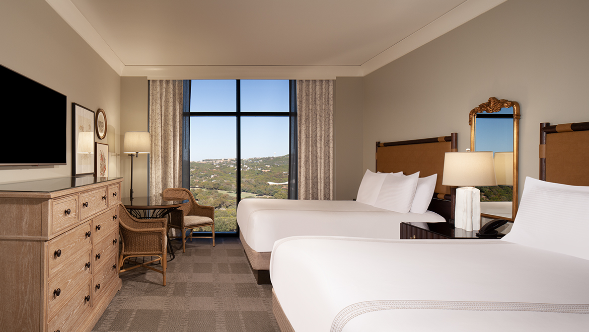 A Premium Queen Room featuring two queen beds and a table with two chairs.
