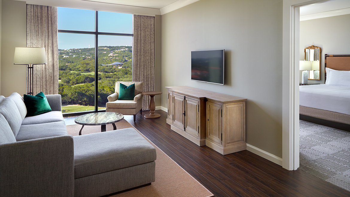 The Signature Fairway Suite living room featuring an l-shaped couch, chair, HDTV and coffee table.