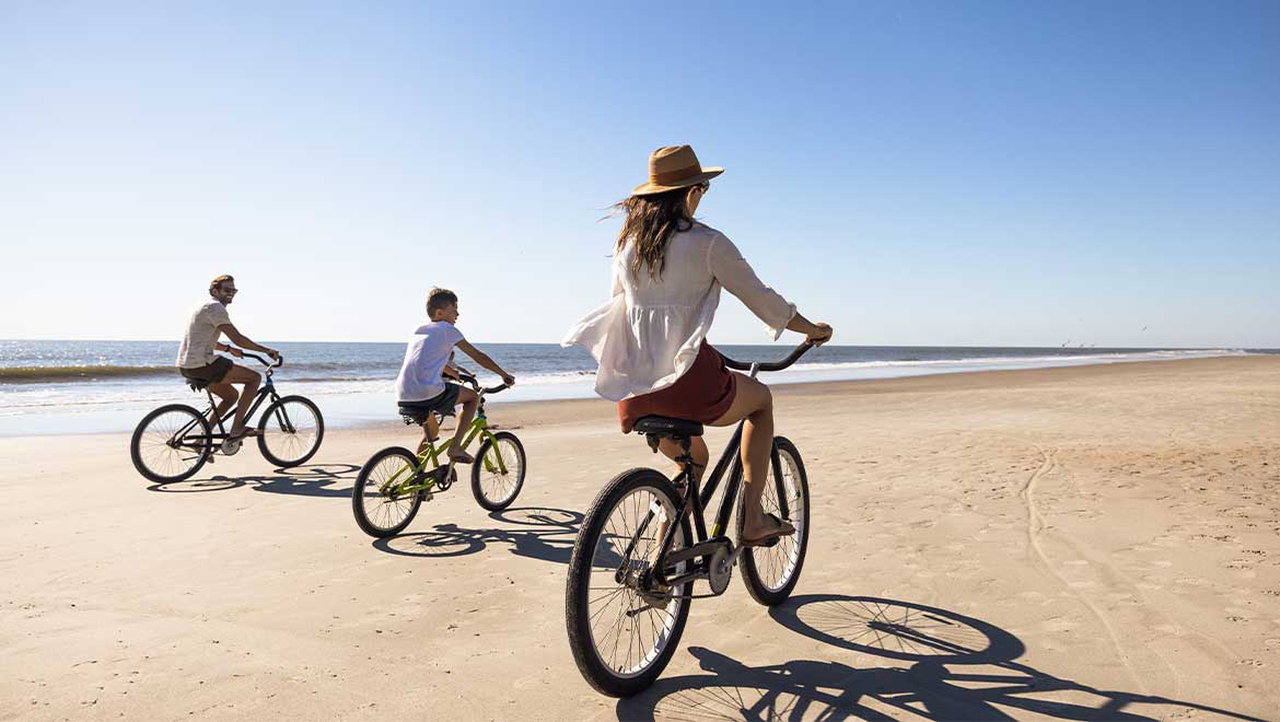 Family riding bikes on the beach