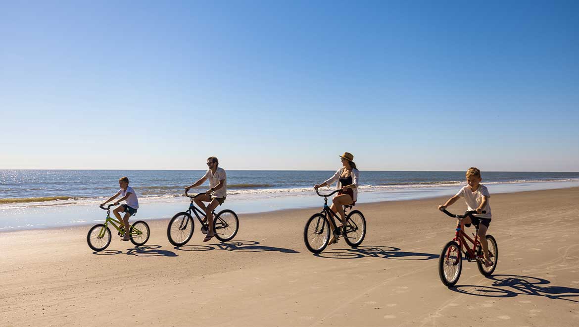 Family riding bikes on the beach