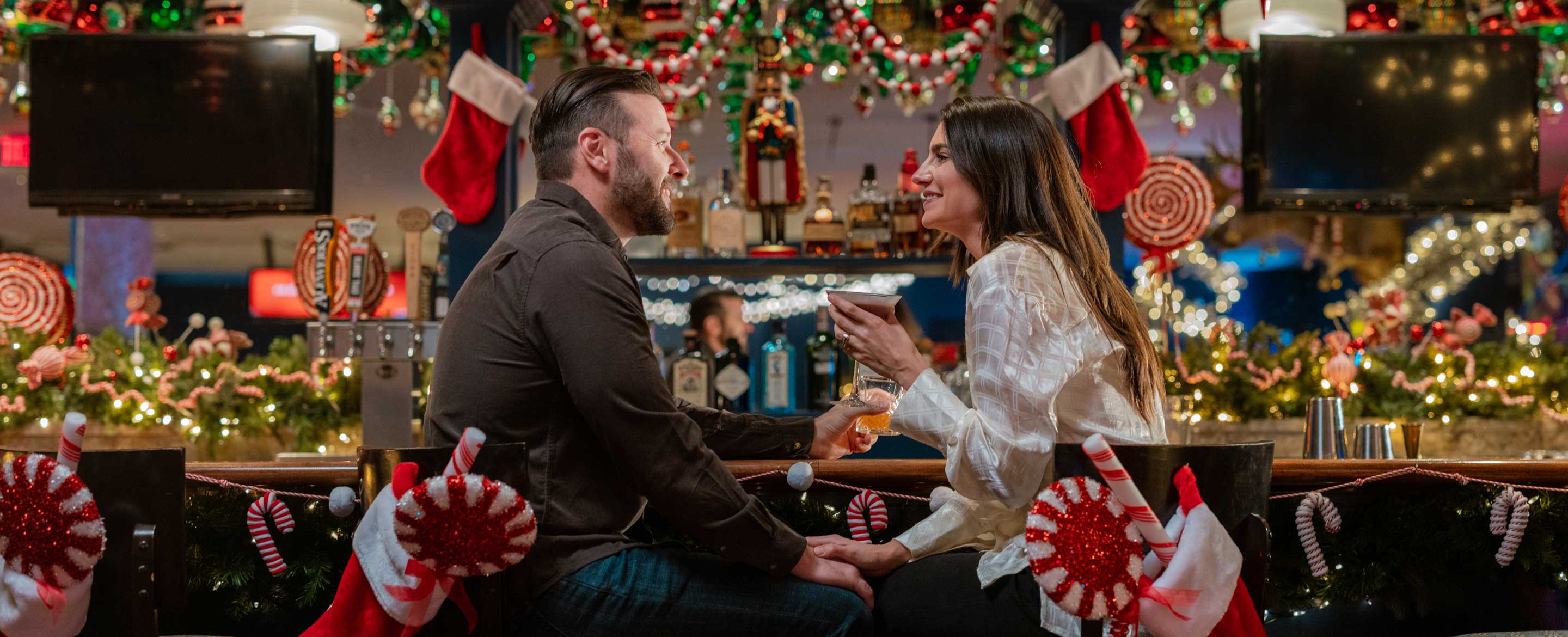 Couple having cocktails in festive bar.