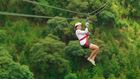 Woman ziplining through trees.