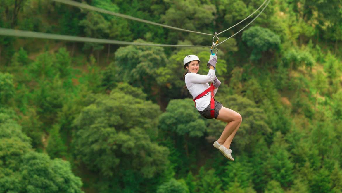 Woman ziplining through trees.