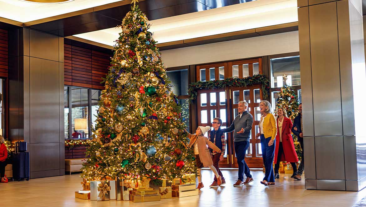 Family admiring Christmas tree in hotel lobby