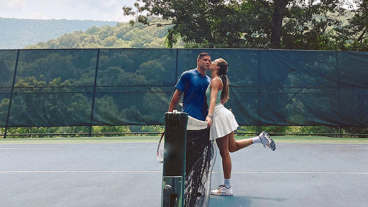 People kissing on tennis court.